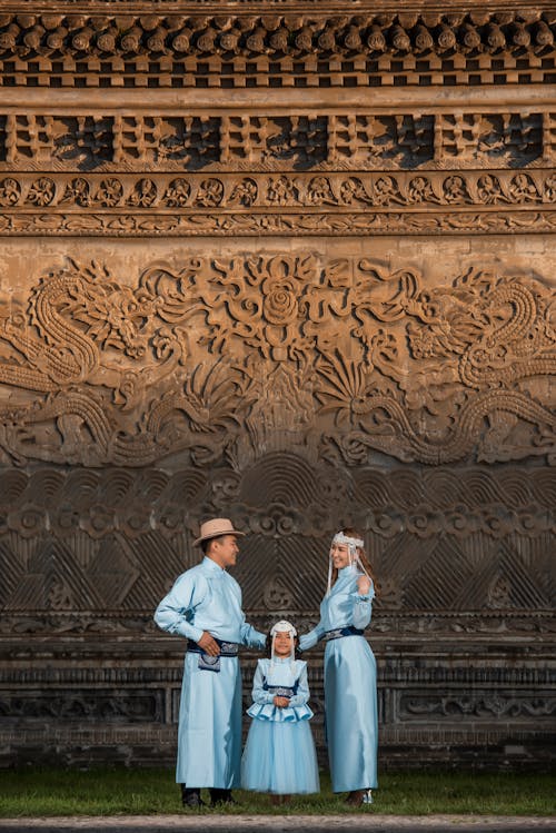 A family in traditional clothing standing in front of a wall
