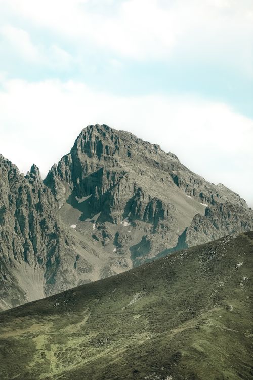 Free A breathtaking view of a rugged mountain peak with lush greenery in the foreground. Stock Photo