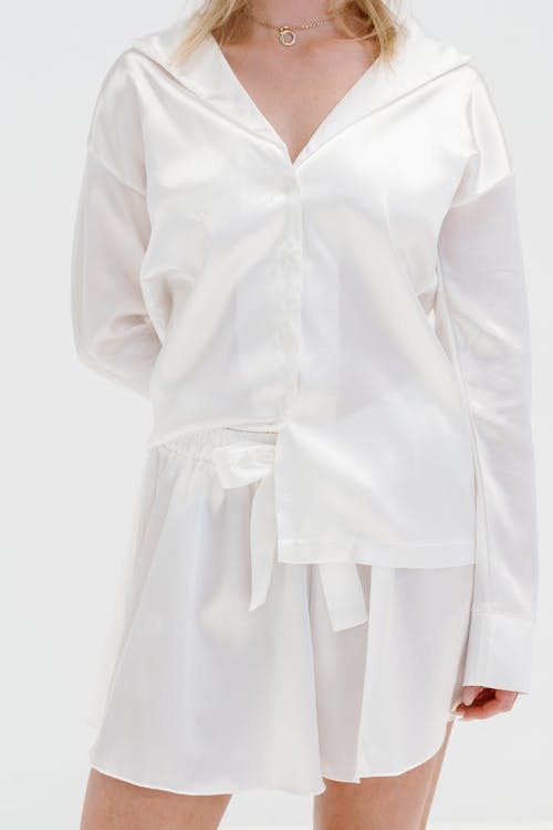The white shirt dress is made from silk and has a tie around the waist