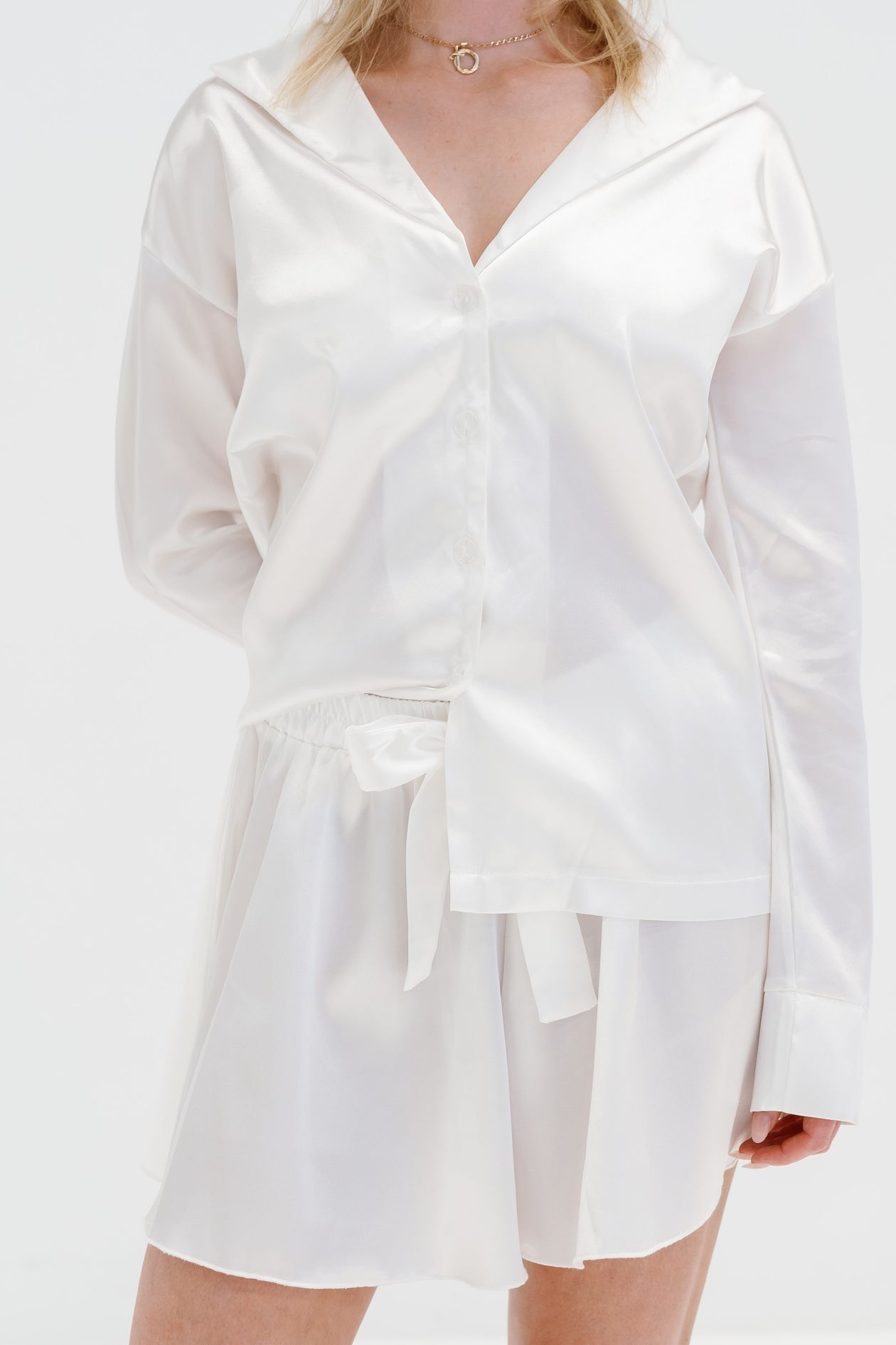 Woman in clean minimalist white shirt and skirt outfit on white background