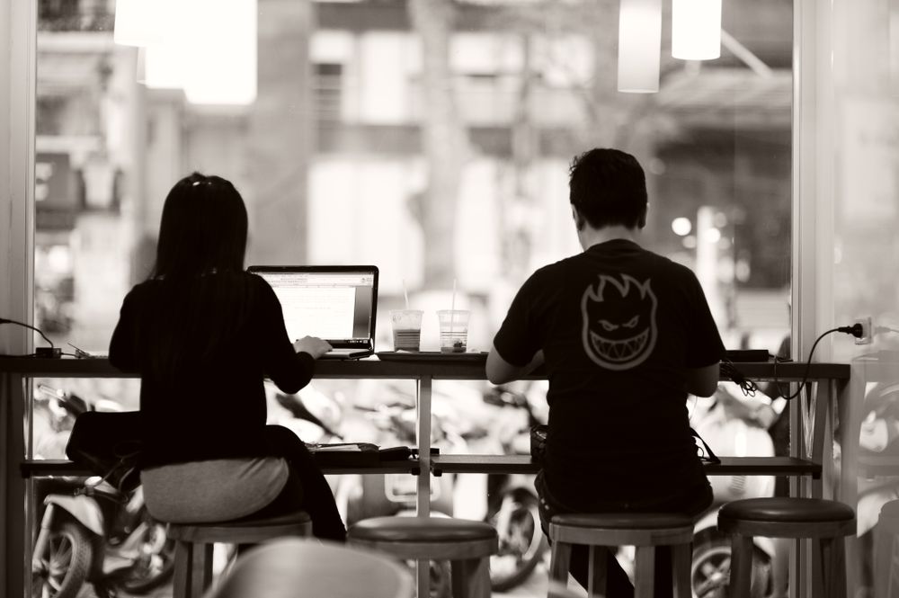 Two people working from laptops at a coffee shop