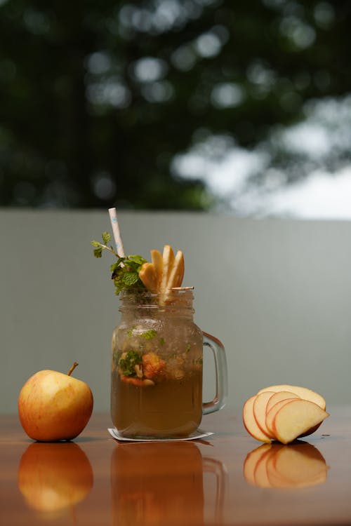 A glass of apple cider with apples and straws