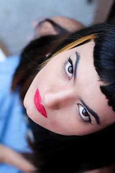 一位妆容大胆、涂着红色口红、向上看的女性特写肖像