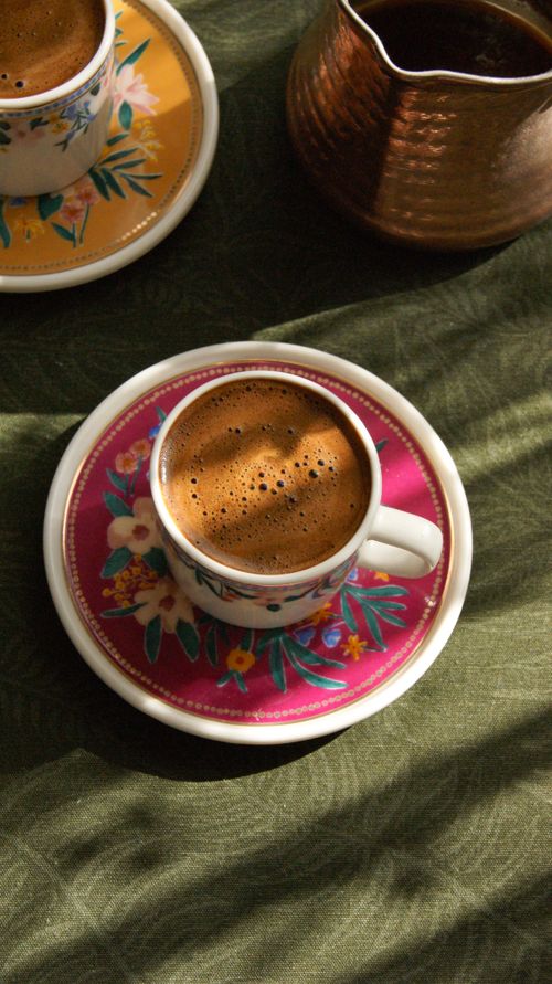 Free Elegant Turkish coffee served in colorful floral decorated cups on a patterned cloth. Stock Photo