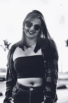 一位自信的女人戴着墨镜，穿着休闲装，在户外微笑着摆姿势