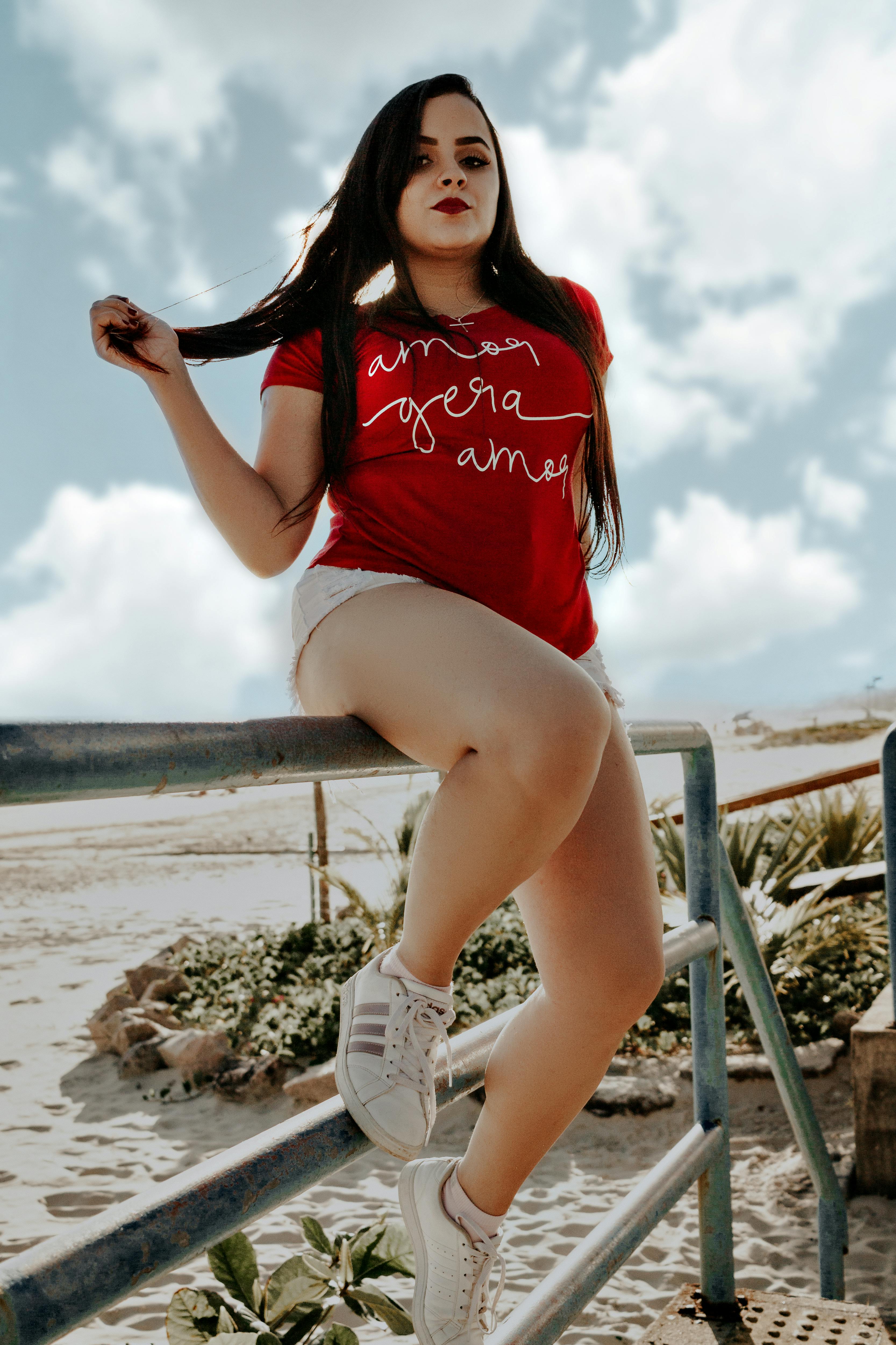 一位穿着红色便服的妇女站在有天空背景的户外扶手旁