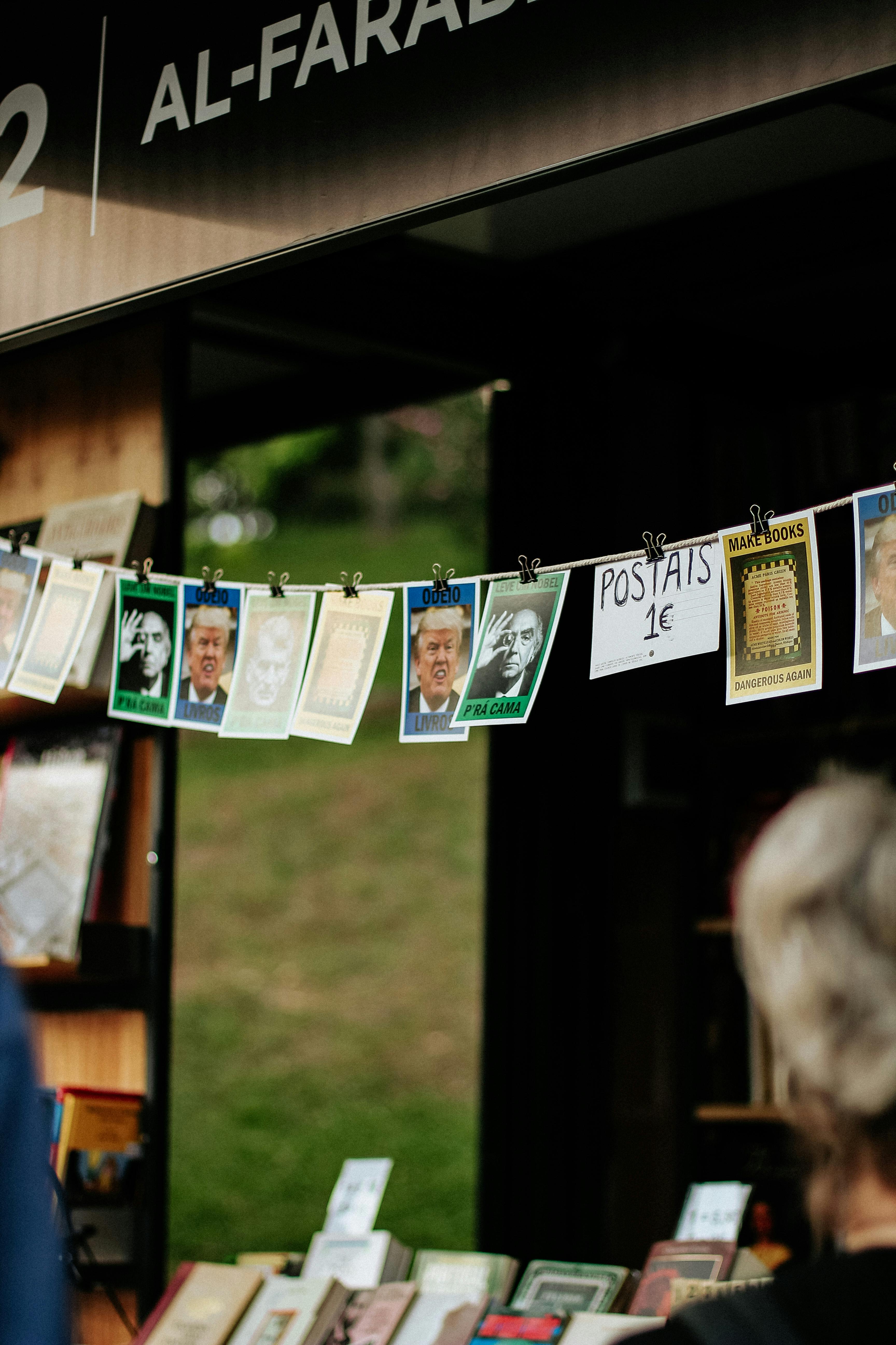 Close-up of various postcards hanging on a line at a vibrant outdoor market stall.