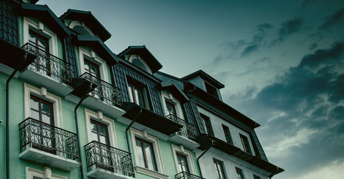 Low-angle view of a residential building with elegant balconies under a dramatic sky.
