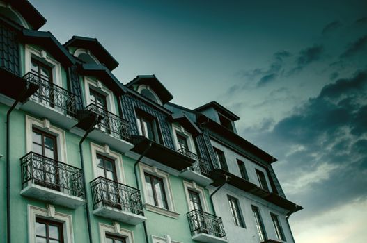 Low-angle view of a residential building with elegant balconies under a dramatic sky.