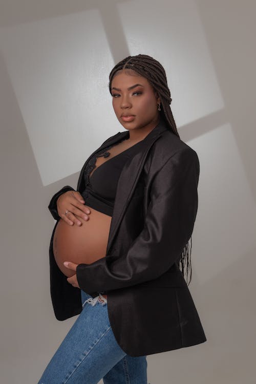 A pregnant woman in a black jacket and jeans