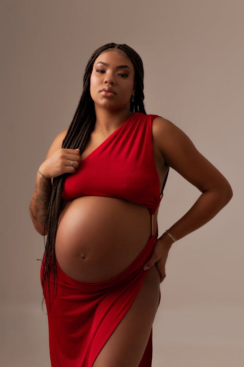 A pregnant woman in a red dress posing for a photo