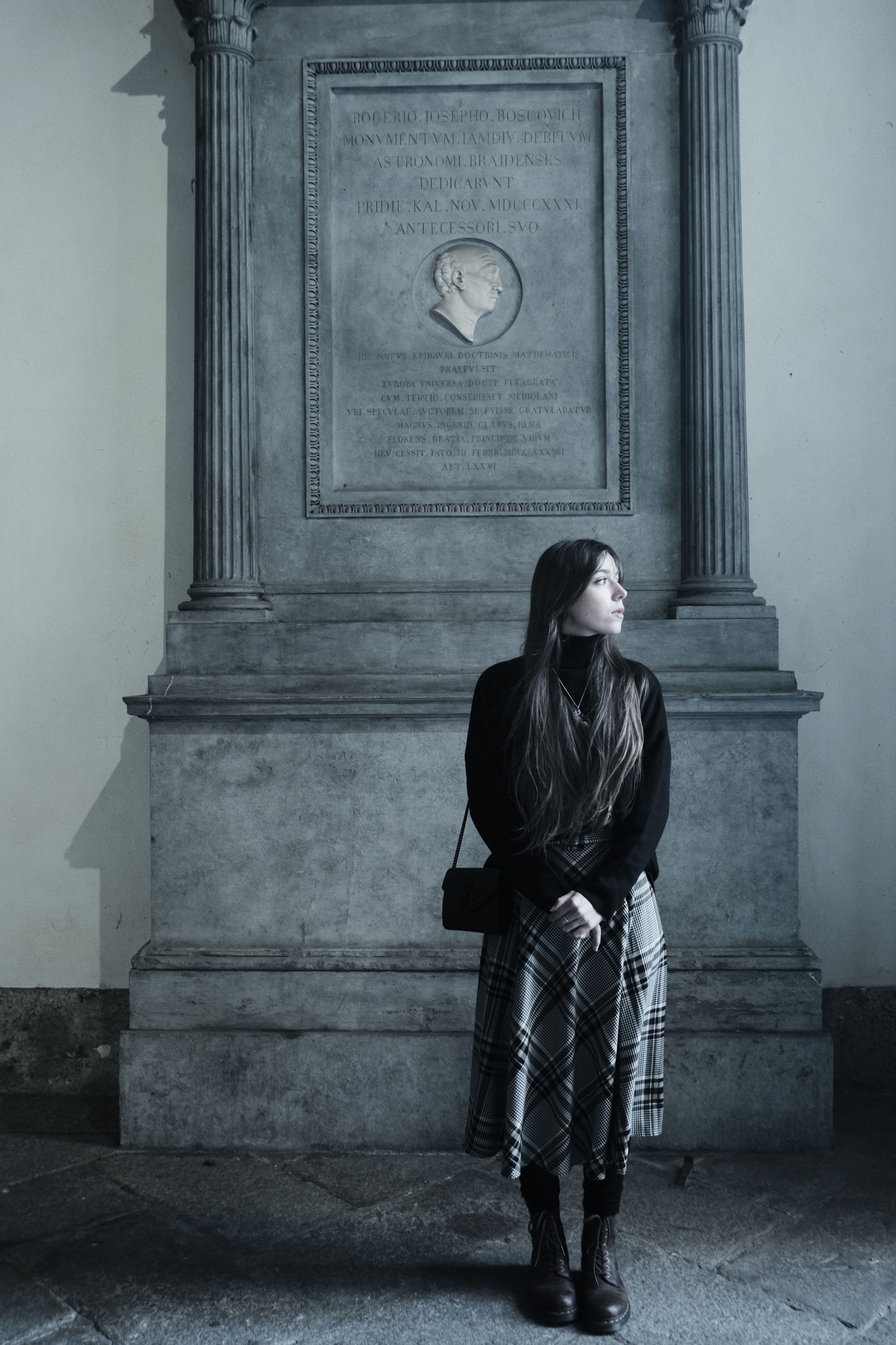 Fashionable young woman standing by Giuseppe Boscovich monument in Milan, Italy.