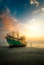 泰国海滩日落时分，一艘废弃渔船的壮丽景色，捕捉了宁静之美与旅行之趣