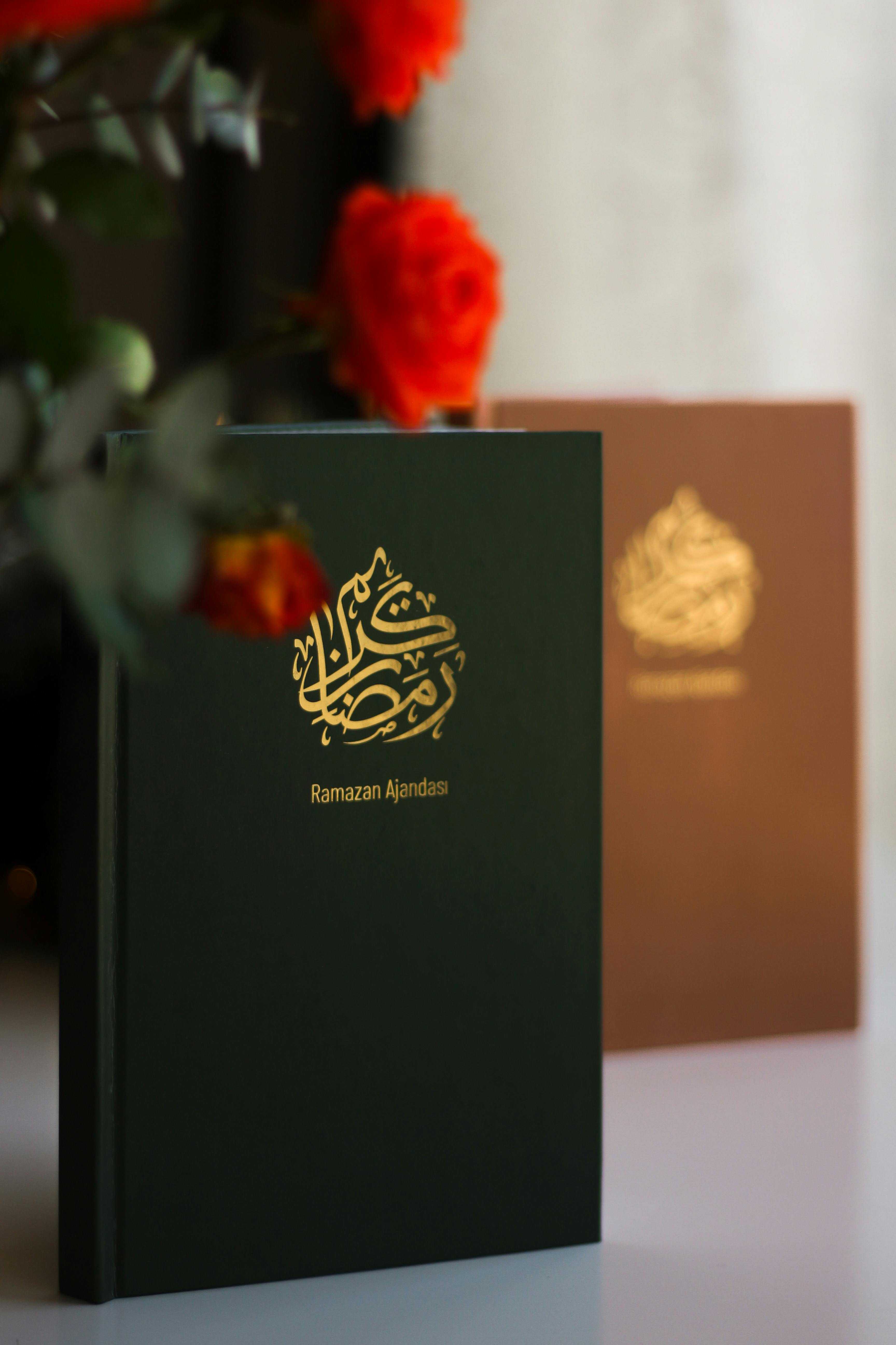 Decorative Ramazan journal with gold Arabic script amidst vibrant red roses for Ramadan reflections.