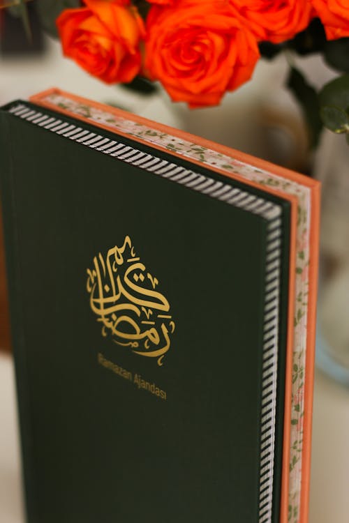 A book with an arabic writing on it and orange flowers