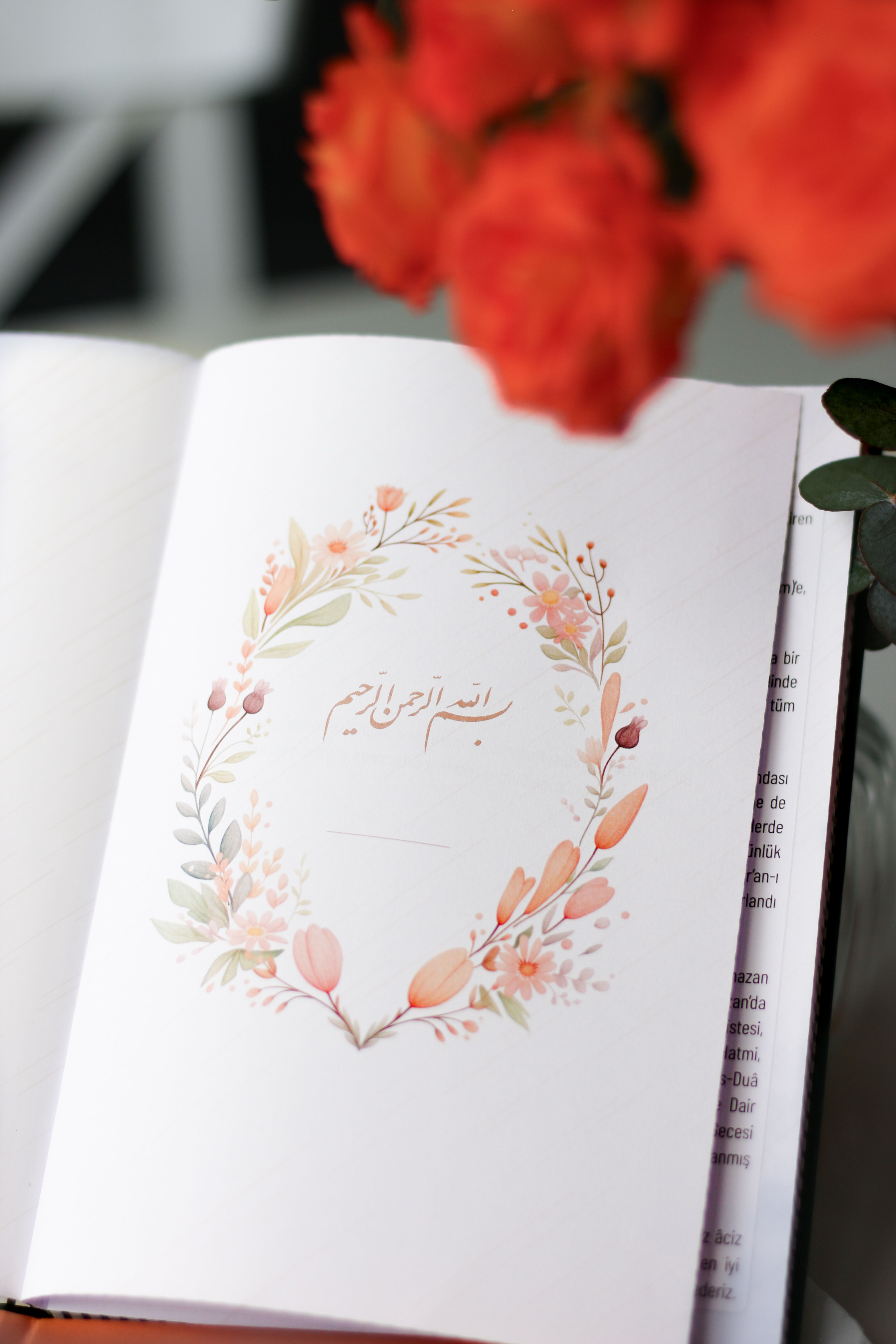 Open notebook with Arabic calligraphy and floral illustration, soft focus.