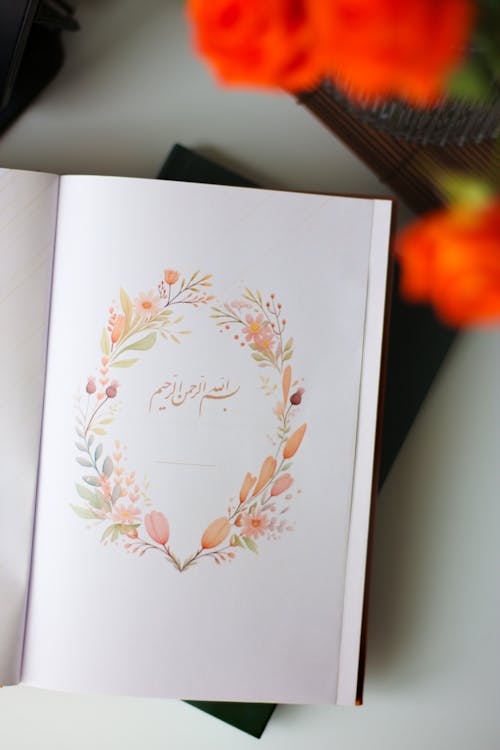 A book with a floral wreath on it and orange flowers