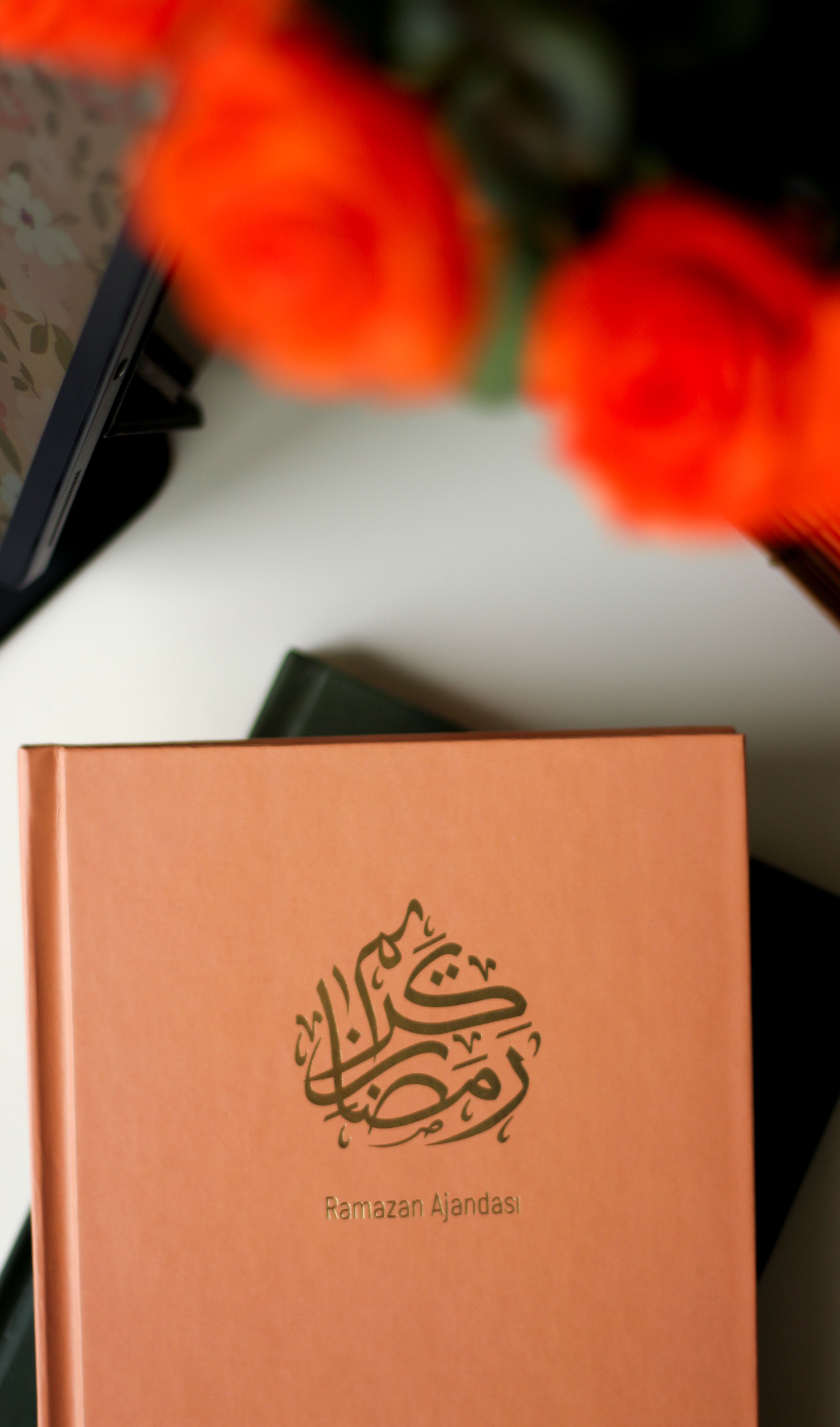 Top view of a Ramadan planner on a table with red flowers.