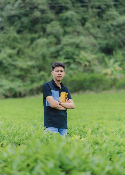 A young man standing in a field with a book