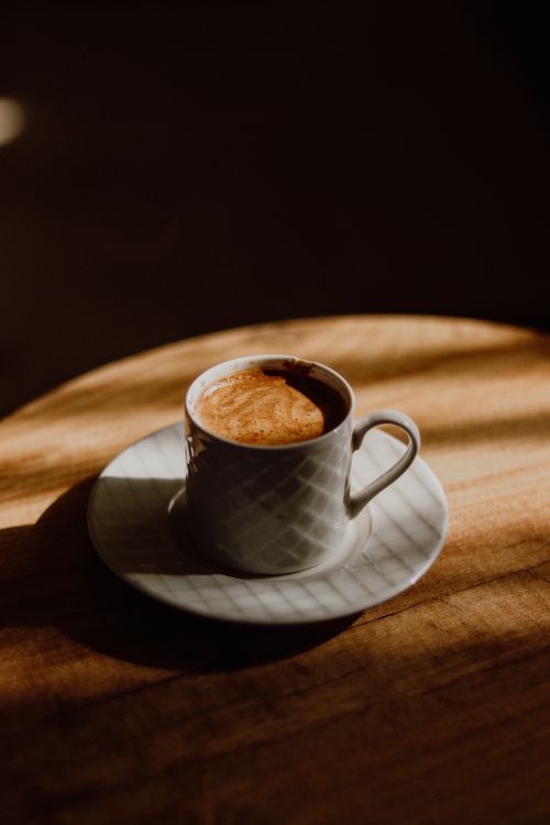 Free A white coffee cup sits elegantly on a wooden table, bathed in warm sunlight. Stock Photo