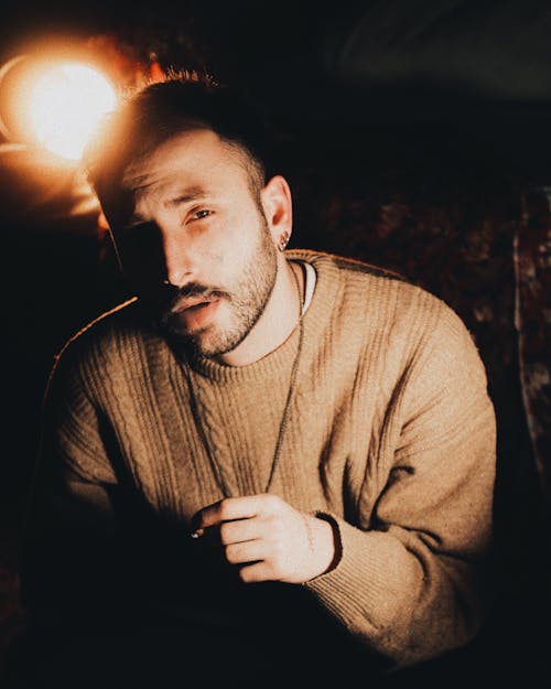 A man in a sweater sitting in front of a light