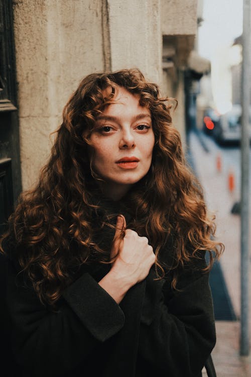 A woman with curly hair leaning against a wall