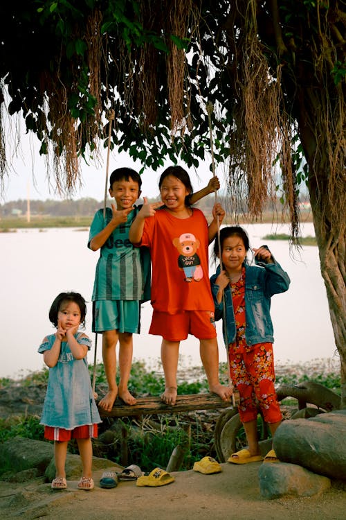 Three children pose for a picture in front of a tree