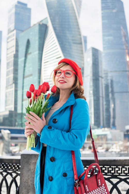 A woman in a blue coat holding red tulips