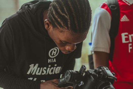 A young adult focuses on adjusting the camera equipment indoors.