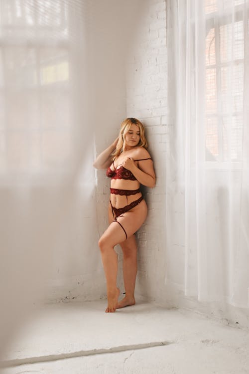 A woman in a red lingerie posing in front of a window