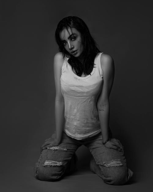 Black and White Studio Shot of a Young Woman in a Tank Top and Ripped Jeans 