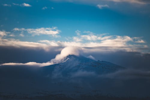 A mountain covered in clouds with a blue sky