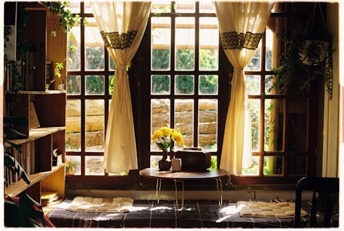A window with curtains and a table with flowers