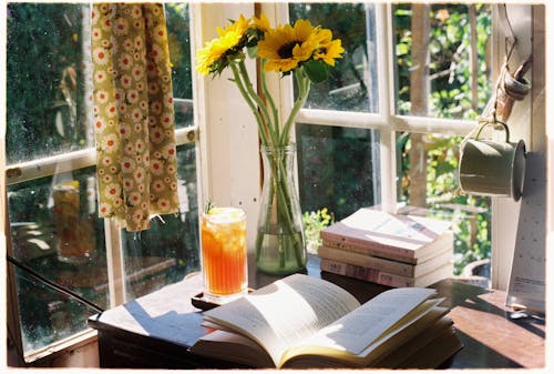 Opened Book by Sunflowers in Glass Vase in Home