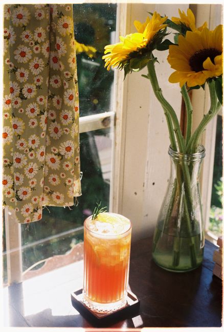 A refreshing iced beverage with sunflowers by a sunny window enhances summer vibes.