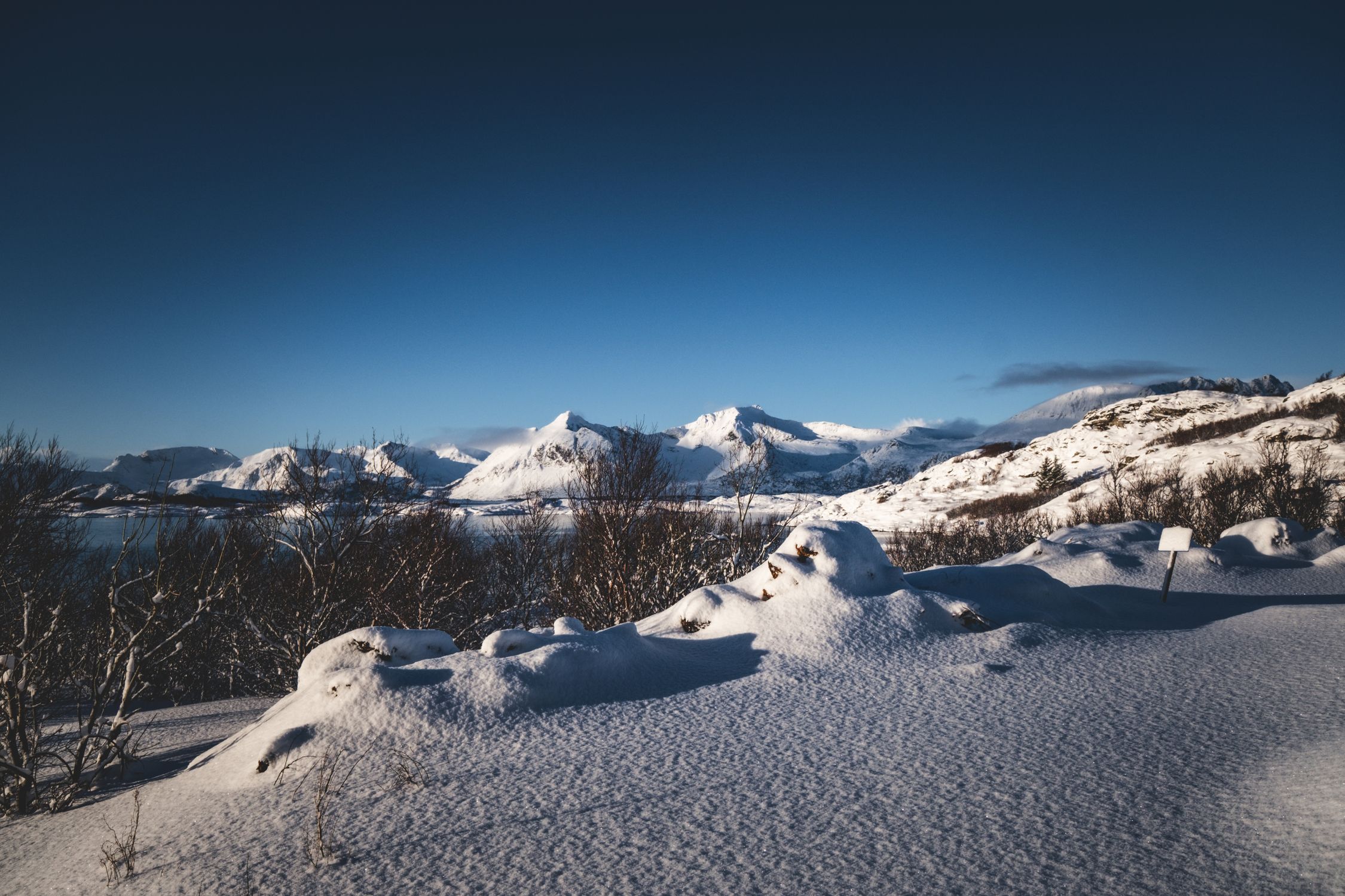 Snow‑covered Arctic mountains under a crisp blue sky in northern Norway
