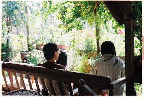 Two people sitting on a bench in front of a garden