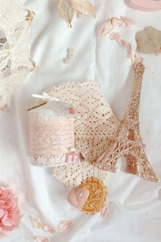 Romantic flat lay featuring Eiffel Tower decoration and lace elements on white background.