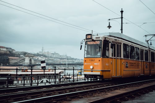 A yellow and white train on tracks next to a city