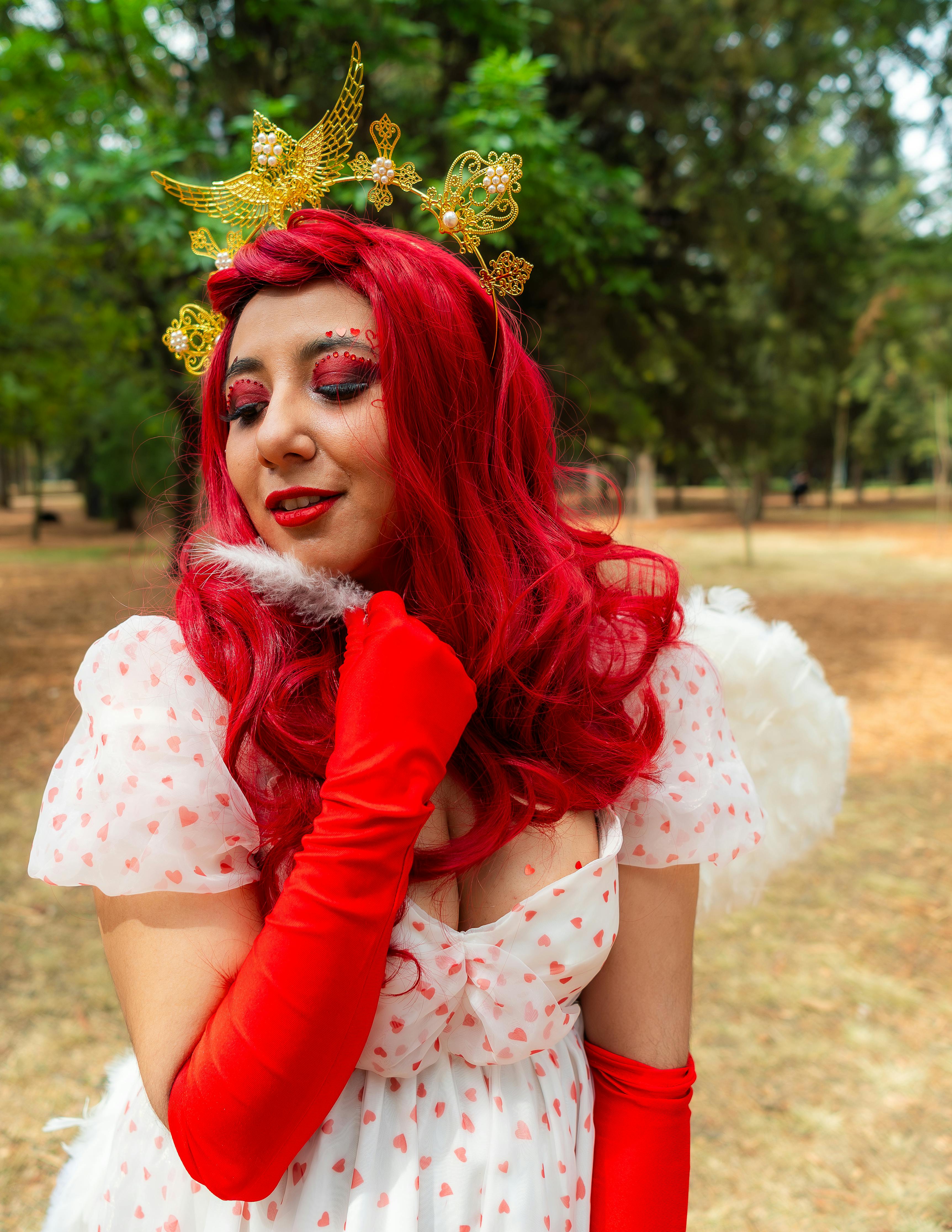 Whimsical portrait of a woman dressed as an angel with a vibrant costume in a lush park setting.
