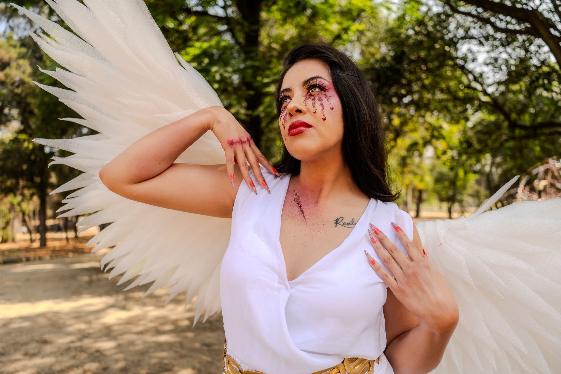 Elegant portrait of a woman with angel wings in a sunny park, embracing serenity.