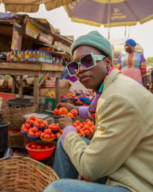 A man in sunglasses and a hat sitting at a market