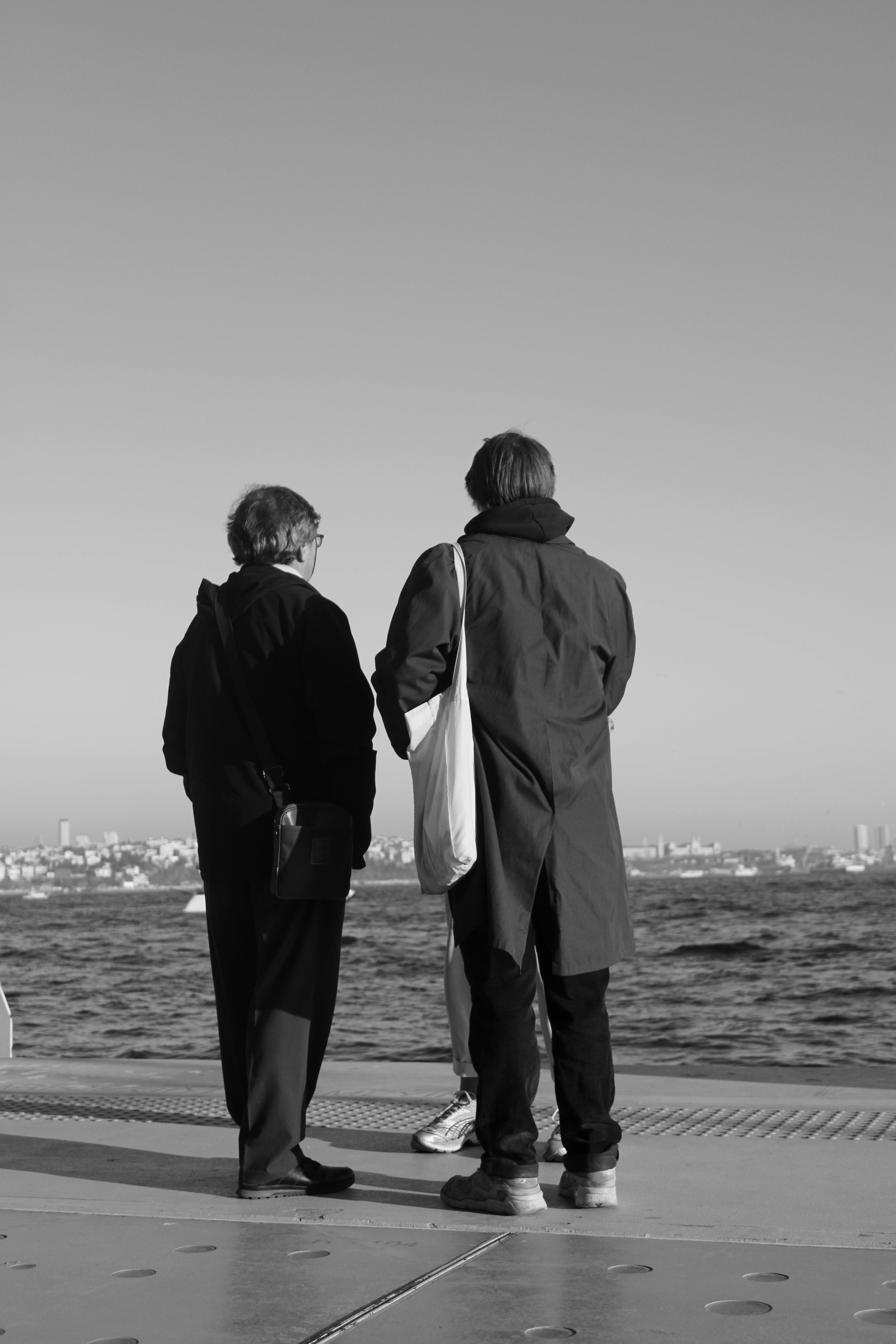 People Standing by the Shore in Black and White · Free Stock Photo