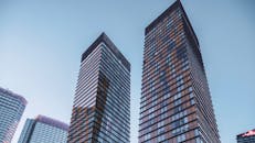 在晴朗的天空下，低角度拍摄的现代摩天大楼玻璃幕墙，展示了城市建筑的魅力