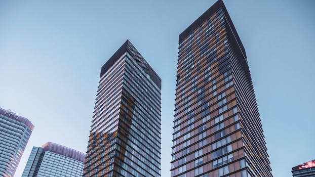 在晴朗的天空下，低角度拍摄的现代摩天大楼玻璃幕墙，展示了城市建筑的魅力