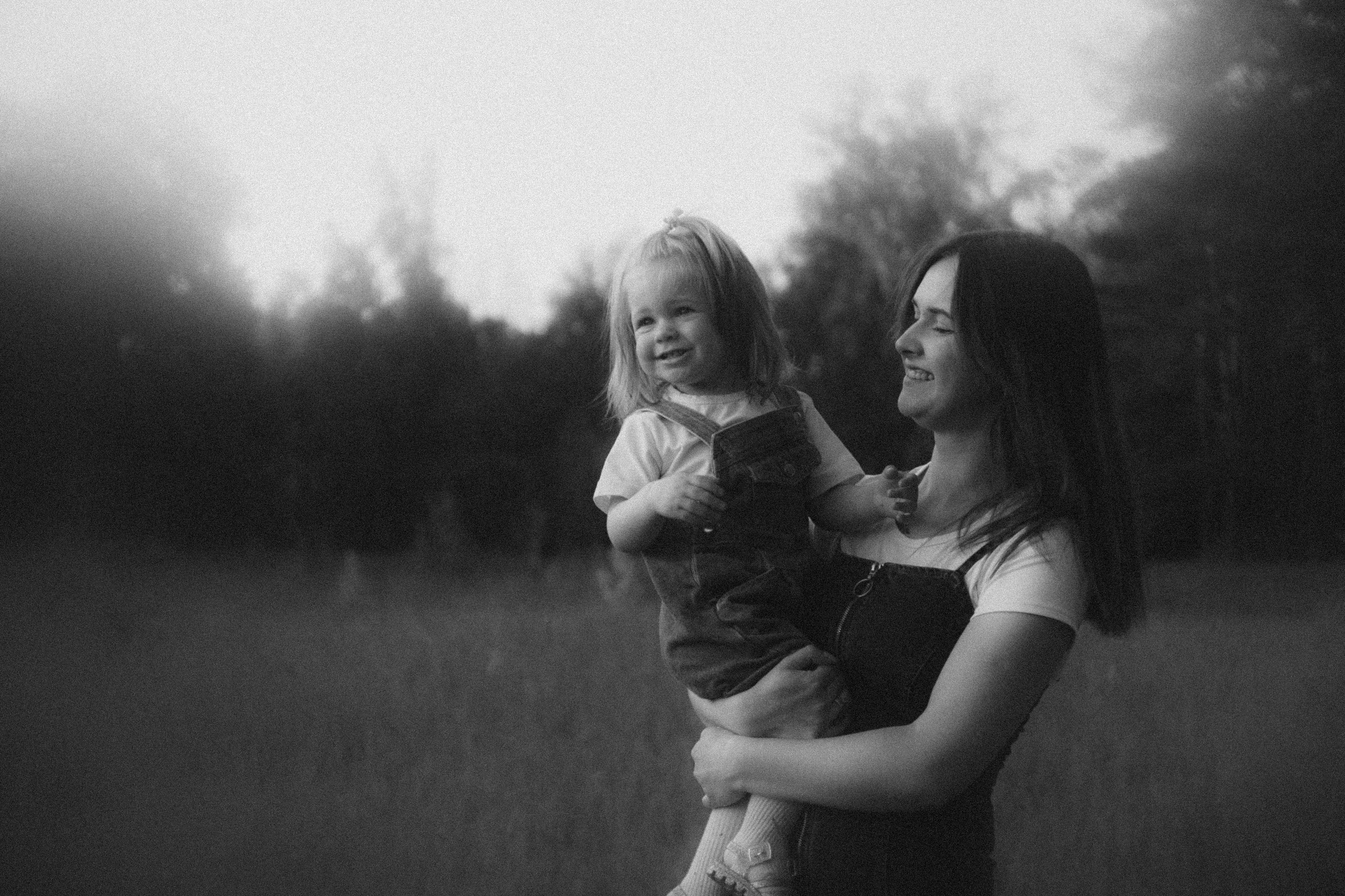 brunette woman holding little girl in hands on meadow