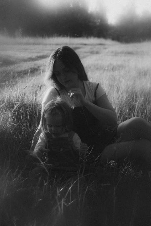 A woman and child sitting in a field
