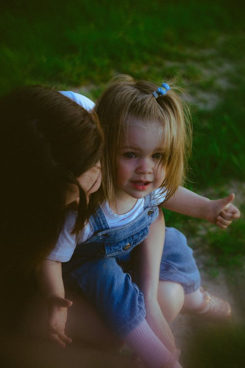 A woman and a little girl are sitting on the grass