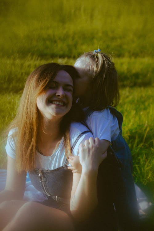 A woman and a little girl are sitting in a field