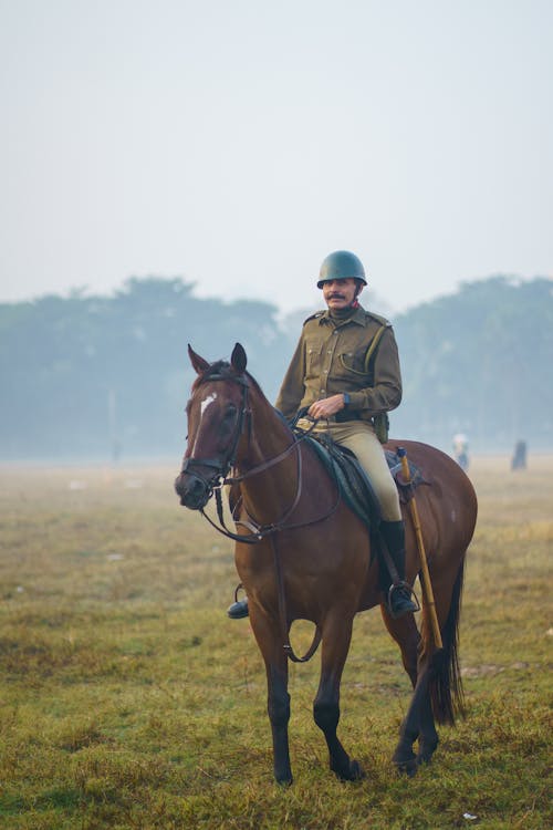 A man in uniform riding a horse in a field